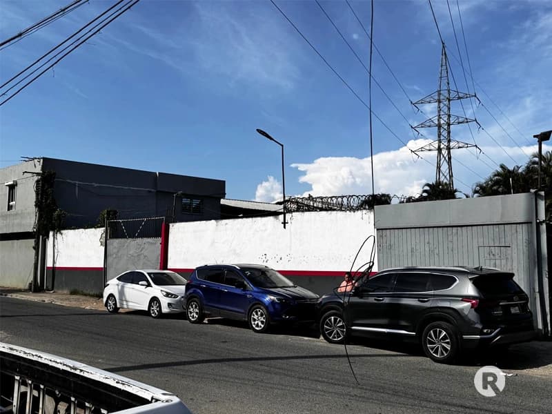 Vista exterior de taller automotriz con pintura desgastada previo a la instalación de revestimiento moderno.